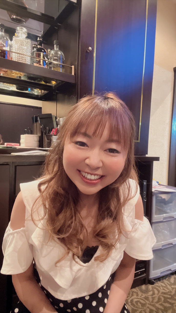Lounge Libertyのママ・きりこ。バックバーのボトル棚を背に、笑顔でお客様を迎えている。